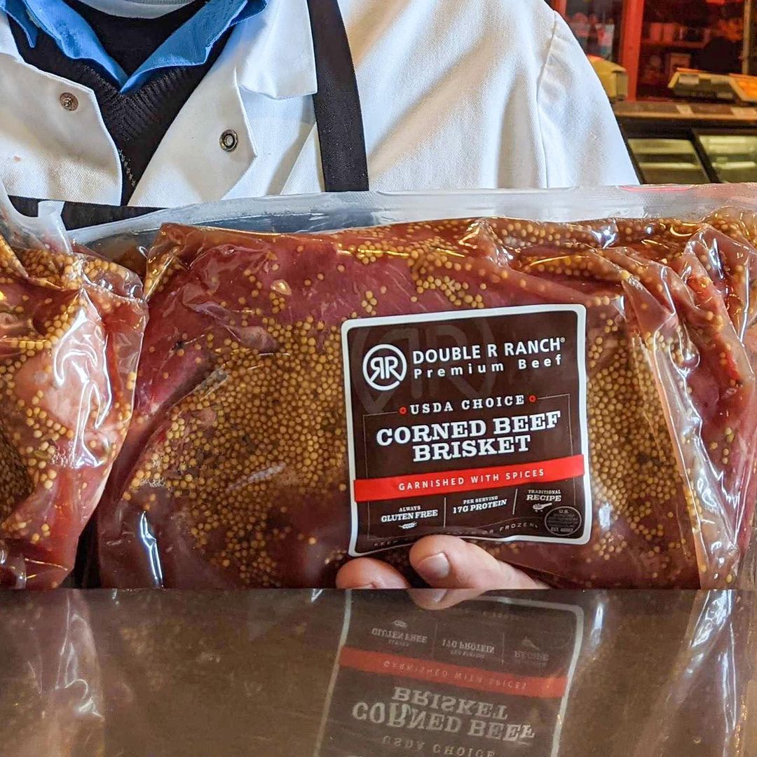 a butcher from don & joe's meats in Pike Place Market holds up a package of corned beef brisket. 