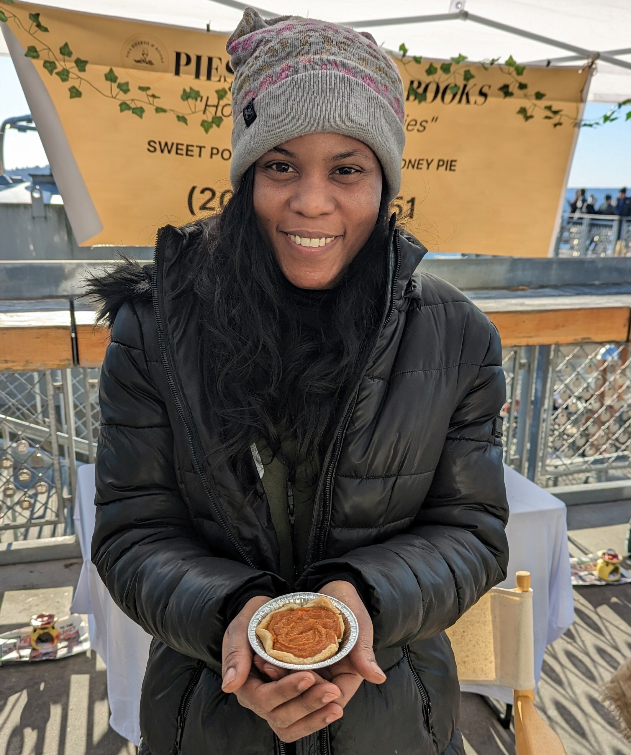 Nadia Moseley holding a personal pie at her stand Pies Boards and Books in Pike Place Market