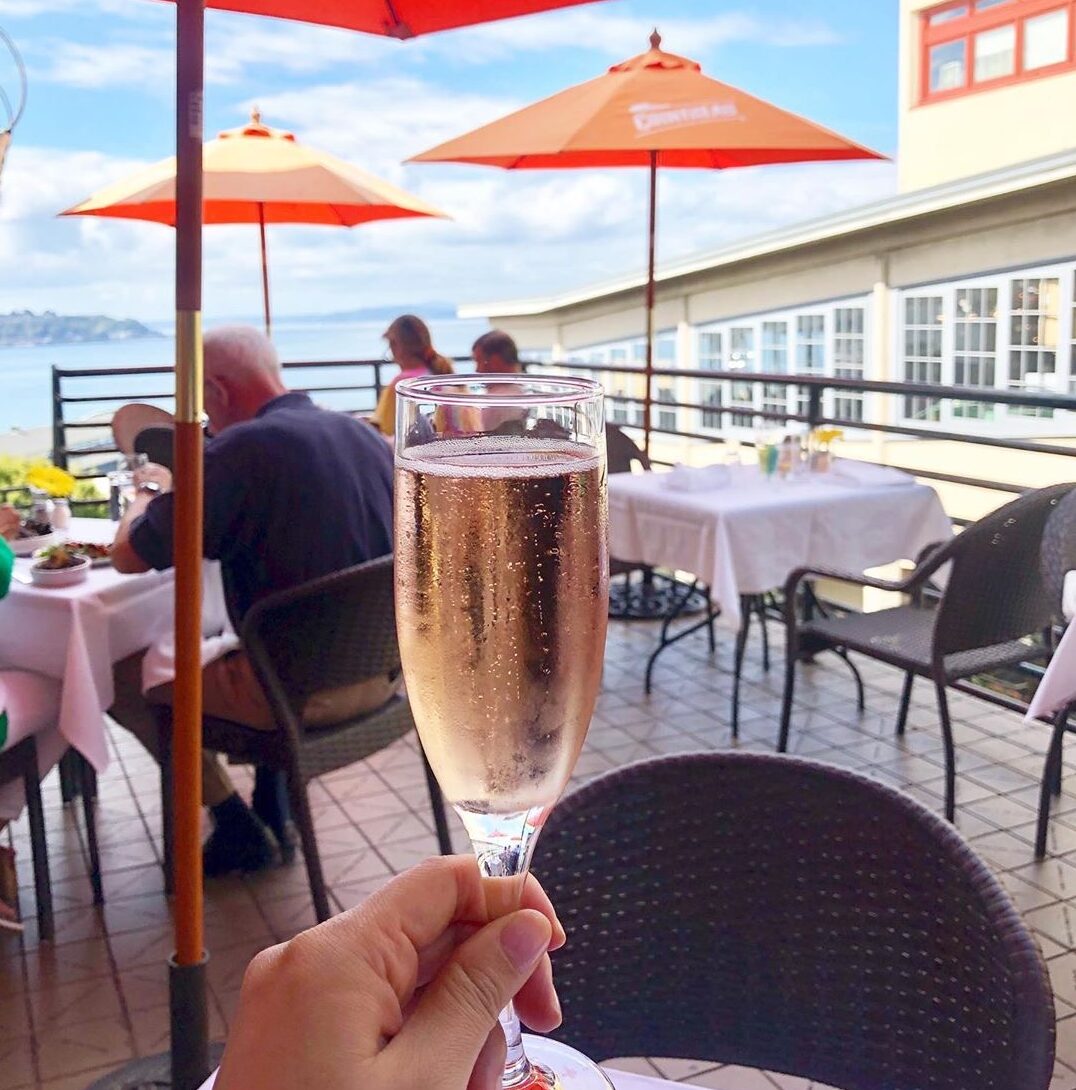 a visitors holds a champagne flute on a waterfront balcony at Place Pigalle in pike place market