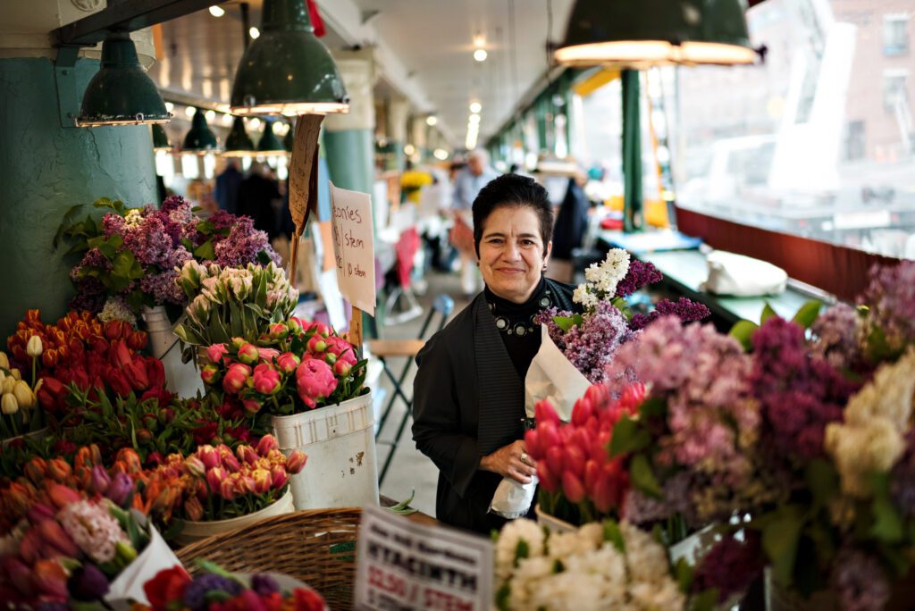 Pike Place Market Executive Director Mary Bacarella standing in front of flowers at Pike Place Market