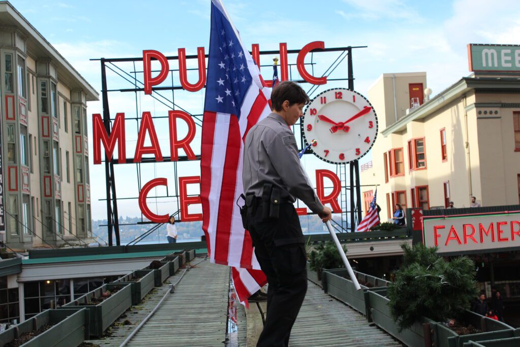 Pike Place Market security officer Liz Teasley helped to put up American flags on the Market's roof during a Veterans Day celebration. 
