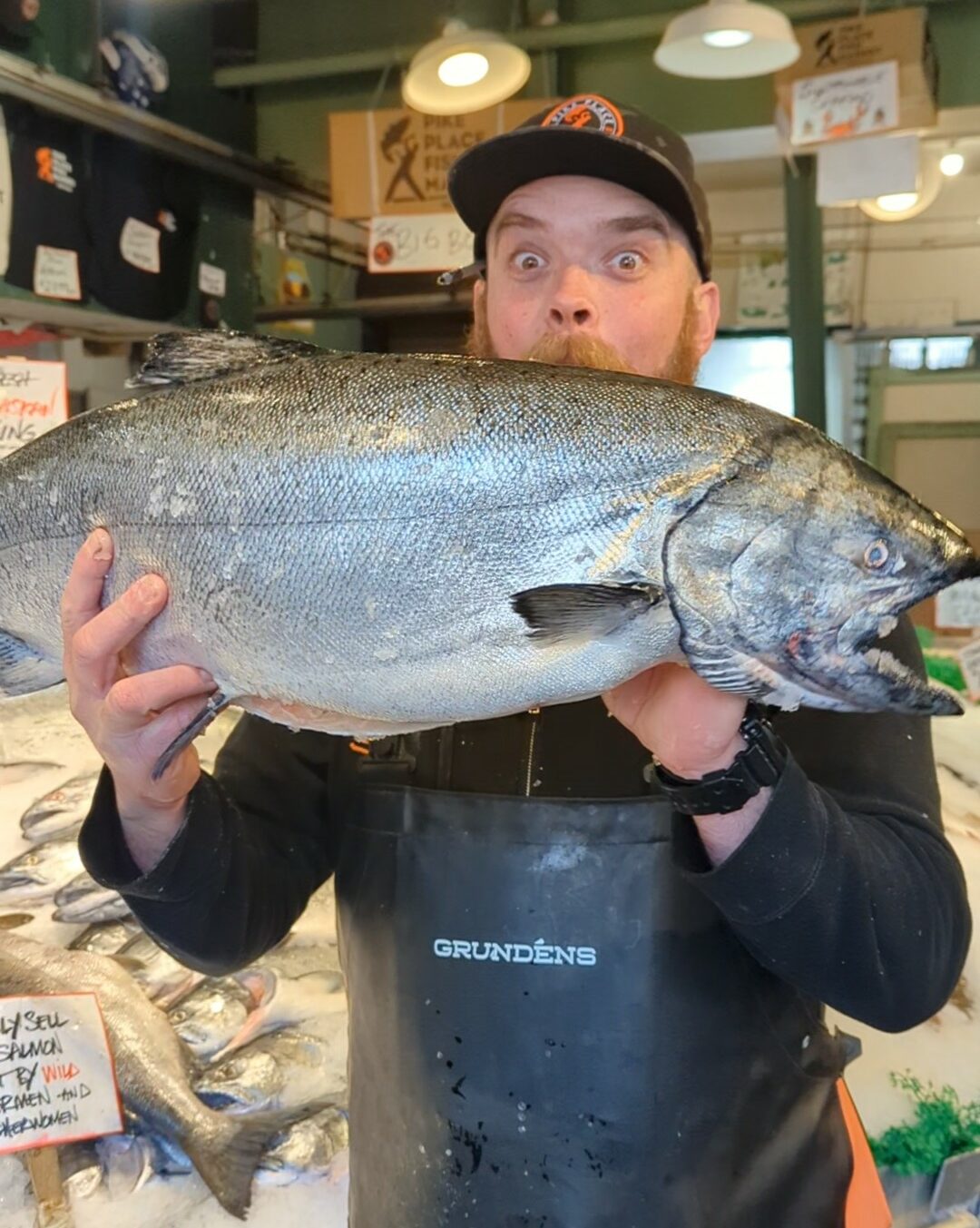 fishmonger holding up salmon at Pike Place Fish in Seattle
