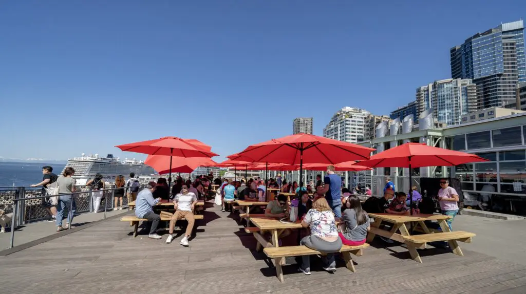dozens of people sitting at picnic tables at a public seating area in Pike Place Market