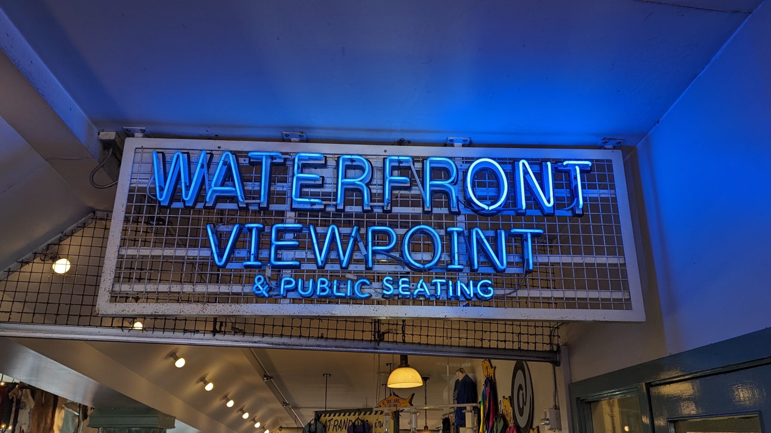 neon sign directing pike place market visitors to public seating and waterfront views at the Market