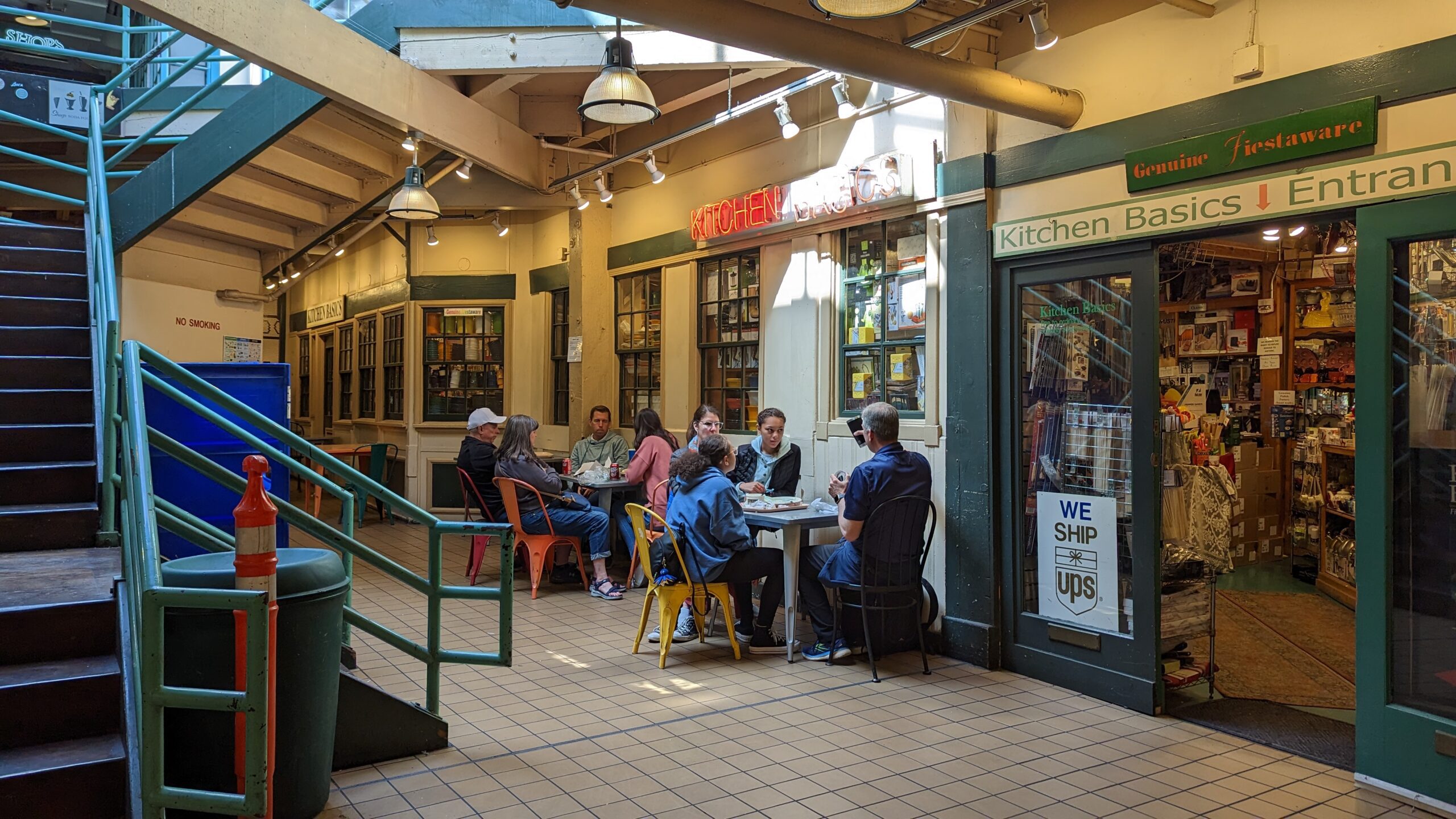 several groups of people sitting in a public seating area at Pike Place Market in Seattle