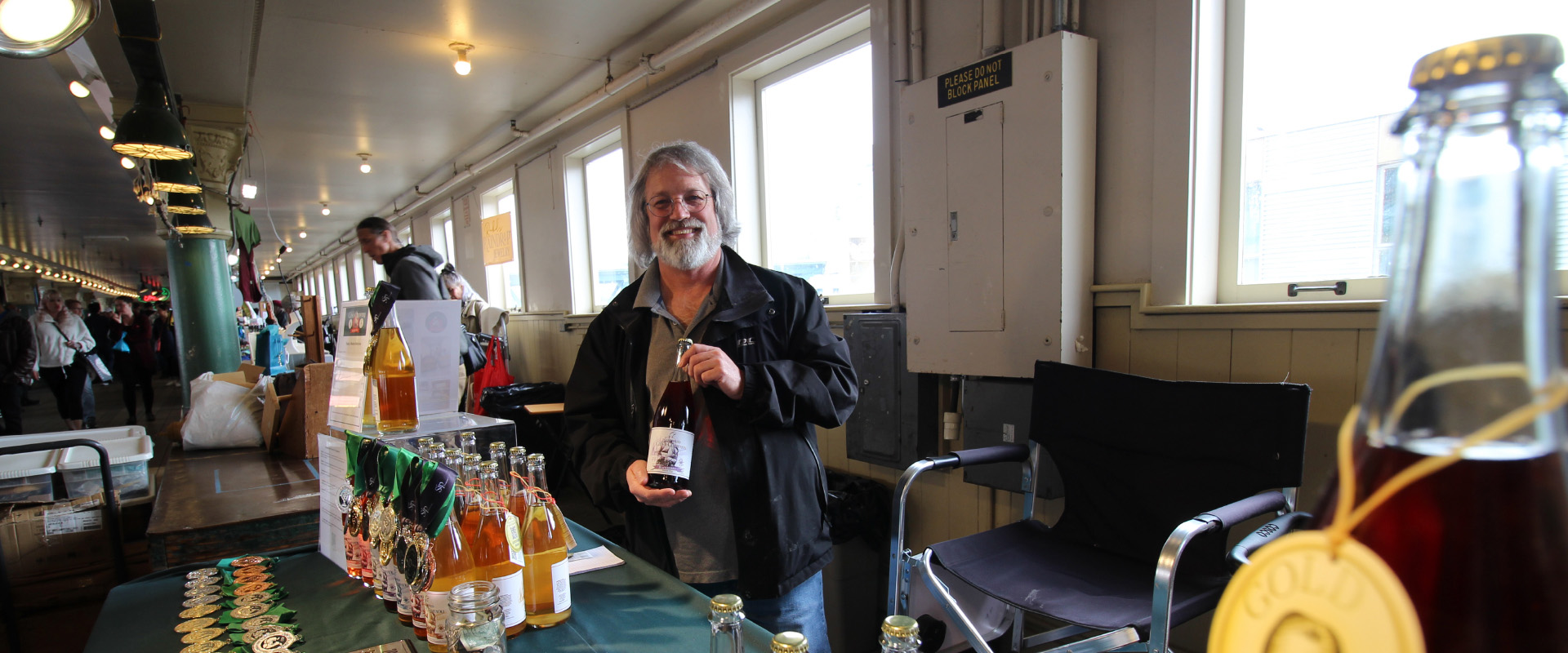 Nick from Puget Sound Cider Company smiles while behind his table in Pike Place Market in Seattle.